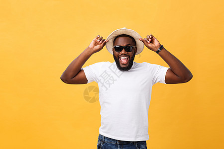 近距离拍摄一个年轻人的肖像 他笑着用手拿着帽子 在黄色背景上被孤立白色快乐黑色男人男性成人微笑图片