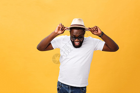 近距离拍摄一个年轻人的肖像 他笑着用手拿着帽子 在黄色背景上被孤立男性成人白色快乐黑色男人微笑图片