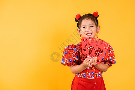 亚裔中国小女孩笑笑快乐 穿着红色长相齐帕奥拿着安格保红包的货币礼物女性裙子传统微笑旗袍文化信封家庭女士庆典图片