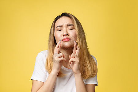 年轻的快乐的亚洲女人 用手指在黄色背景上交叉成人灰色幸福黑发女士女性女孩手势希望微笑图片