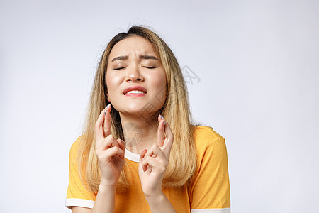 身穿便衣的年轻女性祈祷求神 请抬头看着她用手指穿过灰色背景时所隔绝的一丝不挂情绪欲望白色女孩微笑运气快乐工作室焦虑手势图片