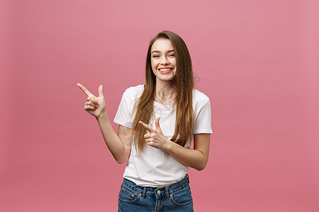 照片中快乐的年轻女性站在粉红色背景上 并用手指摸着她的手指商业青少年成人女士工作室幸福头发牛仔裤手势学生图片