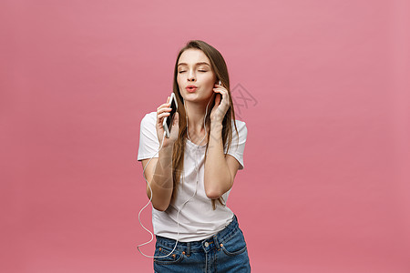 生活方式概念 年轻女性使用电话收听粉红背景音乐的青春妇女耳机成人工具闲暇微笑女士享受歌曲技术舞蹈图片