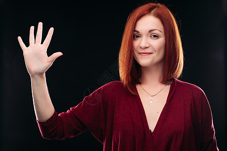 迷人的红发女孩握着手 举起五指图片
