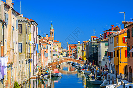 Chioggia市风景 在旧多彩建筑之间有狭窄的水河沟和停泊的多彩轮船图片