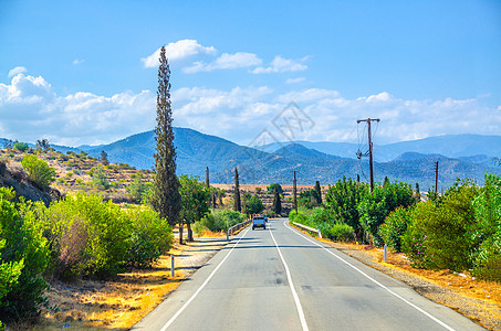 塞浦路斯地貌景观 在河谷的沥青路上乘坐汽车 有黄干田和树图片