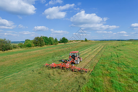 红色的拖拉机在草地上打磨干燥 对现代田间机器的顶级观察图片