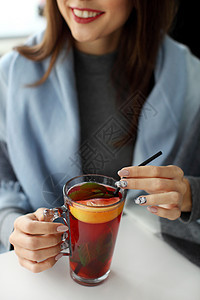 年轻女子握着一杯热薄荷茶或热柠檬水的手咖啡店厨房酒吧女士餐厅调子饮料橙子桌子食物图片