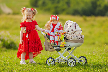 婴儿户外女孩卷起她的洋娃娃带子父母孩子越野车童年公园闲暇季节腰带幸福背景