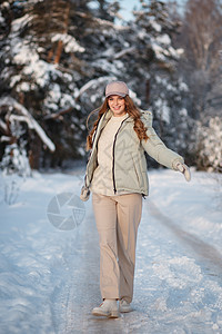 一个模范女孩在雪覆盖的森林中行走 展示着衣服松林喜悦帽子幸福外套女性微笑头发手套森林图片