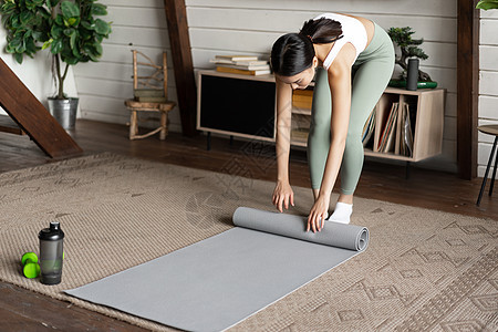 亚洲健身女孩完成训练 在家锻炼 在客厅练习后滚动地板垫等工作重量电脑女孩身体活力运动装互联网瑜伽技术运动图片