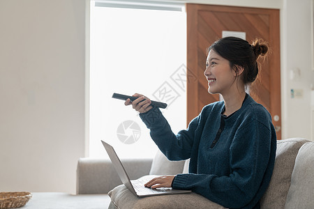 美丽的亚洲女性坐在客厅沙发上 使用笔记本电脑在电视上观看令人兴奋的有趣节目房子女士屏幕微笑娱乐视频闲暇女孩夫妻手表图片