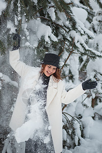 圣诞冬季森林里的模特 站在圣诞树下 雪从圣诞树上掉下来乐趣女孩帽子围巾青少年喜悦公园头发季节幸福图片