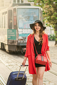 美丽的年轻女孩带着蓝色手提箱走来走去电车商务套装成人旅行裙子帽子女士路面旅游图片