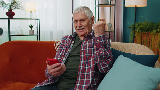 高祖父很快乐 他拥有智能手机 对移动应用程序运动打赌在家中获胜感到兴奋图片