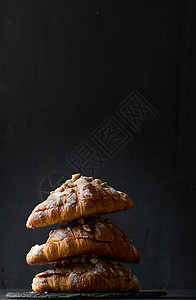 黑背景上洒满粉末糖的烤牛角面包饼堆小吃棕色羊角甜点黄油早餐面包食物乡村白色图片