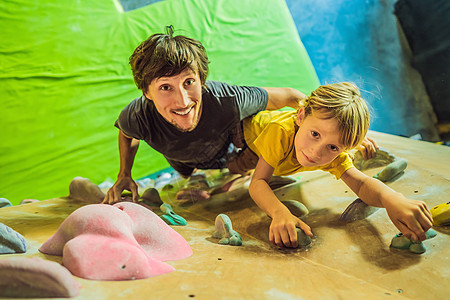爸爸和儿子在攀岩墙 家庭运动 健康生活方式 幸福家庭帮助捆扎女儿孩子冒险训练安全岩石马具男生图片