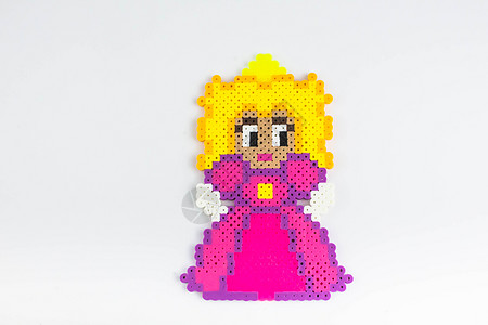 身穿粉红色连衣裙的佩勒珠公主 Perler 珠娃娃穿着粉红色的裙子 白色孤立的背景配饰塑料乐趣童年爱好玩具植物娃娃工艺晴天图片