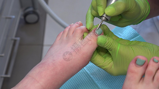 使用钻孔工具切掉旧脚趾甲 在美甲沙龙做内科护理图片