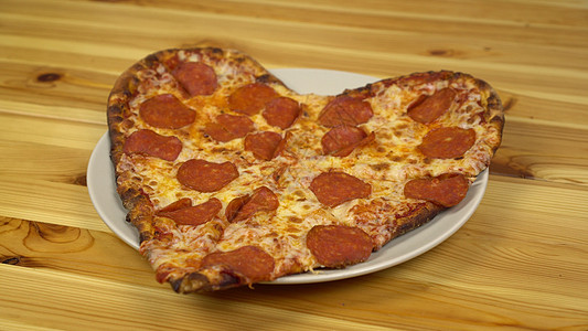情人节的一天 披萨以心的形式呈现在木制桌子上的板块上图片