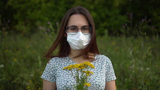 身戴医疗面具的年轻女子嗅闻鲜花 因为不闻而摇头 她戴着眼镜 穿着自然服饰过敏疾病模式医院疫苗屏蔽药品花粉女孩口罩图片