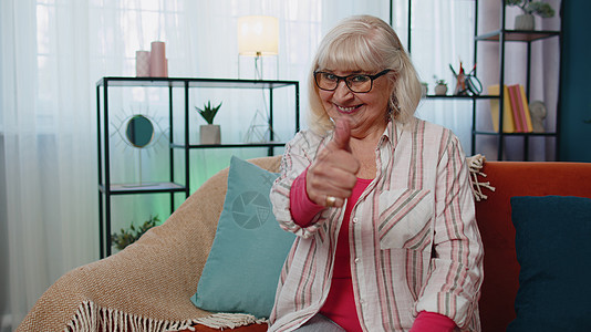 奶奶老太婆看着照相机 抬起拇指 同意家里有好东西的喜悦客厅手指胜利广告手势成就微笑老年退休祖父母图片