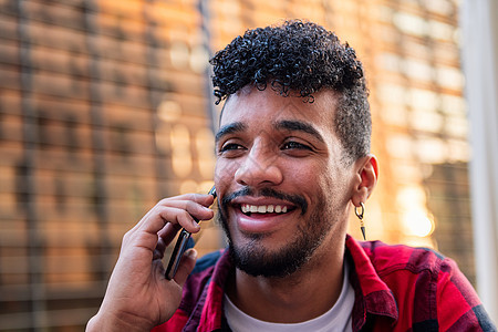 年轻拉丁男人在电话里说话 笑着微笑细胞城市商业喜悦技术成人男性快乐学生青少年图片