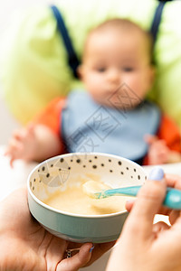 快乐的婴儿用勺子吃食物 快乐男孩坐在高椅子上的肖像用餐游客稀饭家庭桌子食欲营养孩子午餐旅游图片