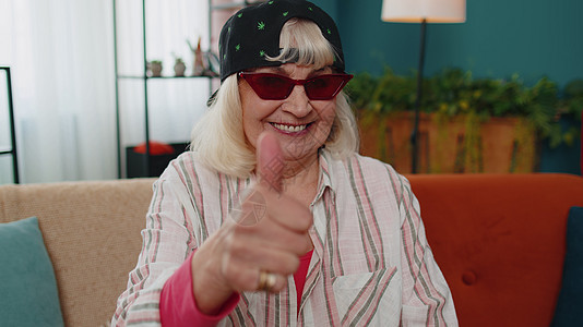 奶奶老太婆看着照相机 抬起拇指 同意家里有好东西的喜悦祖父母老人手势女士退休服装成就老年手指广告图片