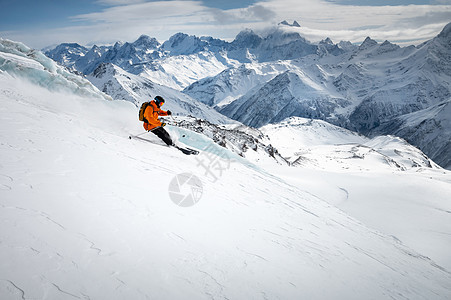 在阳光明媚的日子里 在冰川和高雪山的背景下 专业滑雪者在雪坡上快速骑行 滑雪场空间复制介绍下坡天空运动季节太阳男人旅行自由行动速图片