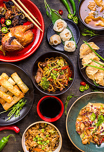 筷子夹各种中国食品组春卷饺子胡椒午餐点心盘子炒锅零食筷子桌子背景