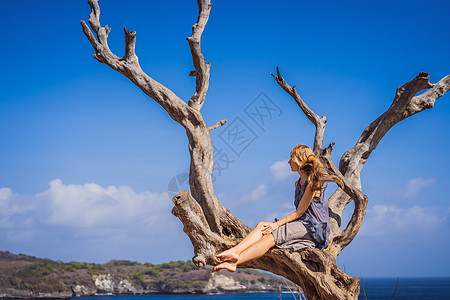 在印度尼西亚巴厘岛努沙佩尼达的海天使比拉邦背景下坐在树上的妇女 巴厘旅行概念墙纸海岸自由海洋旅游海滩岩石游客成人海岸线图片