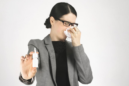 穿灰色夹克的年轻女子用餐巾打喷嚏 当着她的面拿着鼻涕喷雾图片