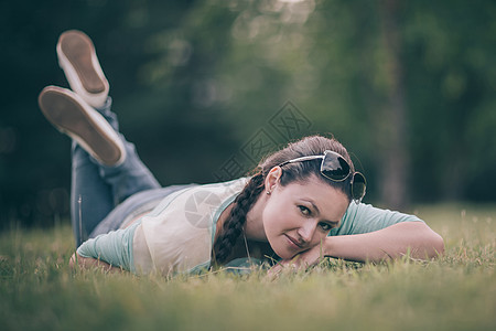 可爱的年轻女人躺在绿草地上图片