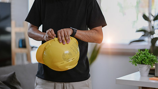 无法辨认的建筑工人拿着黄色硬帽手持黄帽子图片