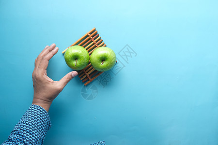 在蓝背景顶视图上 手持绿苹果背景图片