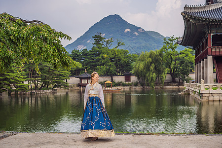 在韩国宫殿穿着韩服的年轻白人女游客 前往韩国的概念 韩国民族服装 游客娱乐试穿韩国民族服饰文化裙子建筑学衣服国家地标街道城市女孩图片
