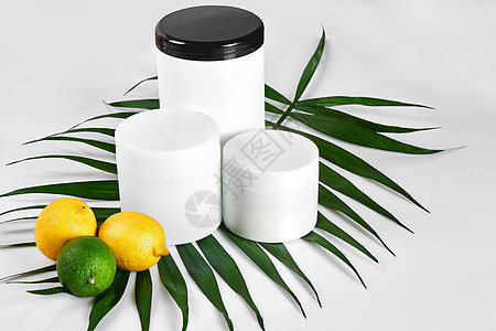 白色瓶子和两个整个柠檬和石灰隔离在白色背景 广告化妆品的概念软木塑料团体水果香水添加剂家务洗发水淋浴静物图片