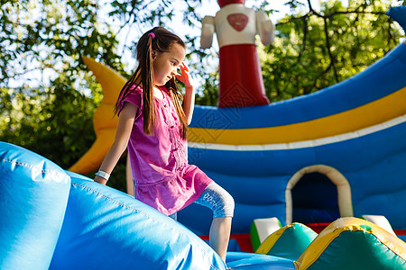 快乐的小女孩在滑动期间 在跳跃城堡上玩得很开心蹦床童年空气微笑孩子活动游戏派对喜悦乐趣图片