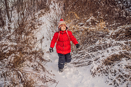 穿红冬服的可爱男孩在雪中玩得很开心 冬季乐趣出门概念新年童年活力天气跑步衣服孩子婴儿家庭季节图片