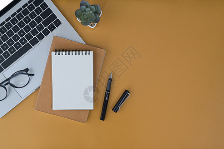 黄色背景的笔记本电脑 笔记本和眼镜 平坦的 时髦的工作场所图片