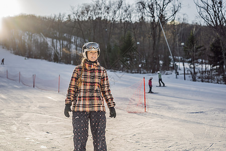 在滑雪度假胜地的阳光明媚的冬日女孩们季节蓝色高山爬坡闲暇微笑风镜行动手套图片