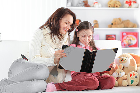 有魅力的母亲和女儿在沙发上读一本书 照片附影空间图片