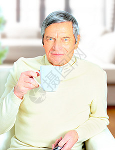 高年男子拿着咖啡杯的肖像 对着镜头微笑退休眼睛男人成人男性咖啡老年杯子沙发相机图片