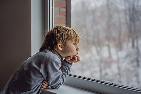 圣诞节那天或早上 快乐可爱的男孩坐在窗边 看着外面的雪 微笑的孩子着迷于降雪和大雪花眼睛毛衣男生运输游客铁路旅行男性乐趣乘客图片