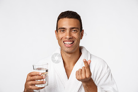 一个有魅力的男人 在白色背景下 喝杯水的好男人健康微笑瓶子男性成人快乐爆炸玻璃幸福手指图片