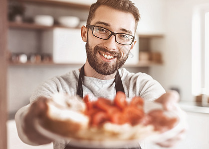 一个有魅力的男人手里的三明治 夹在一个漂亮的男人手中盘子丈夫营养眼镜早餐烹饪面包围裙桌子男性图片