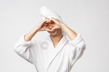 美人 温泉和休闲概念 穿着浴袍和浴巾的可爱的亚洲男子 在脸上露出耳印并微笑 保持乐观 享受酒店休息时间 白底背景毛巾洗澡成人淋浴图片
