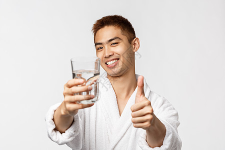 美人 温泉和技术概念 浴袍中满意的英俊亚洲男子肖像保持健康 觉醒和喝水 握着玻璃并举起拇指 建议生活方式洗澡喜悦酒店男朋友成人男图片