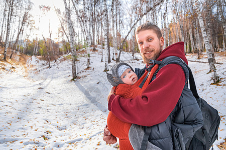可爱的微笑笑容 长着胡须胡子的婴儿装扮父亲 带着孩子在秋林中行走图片